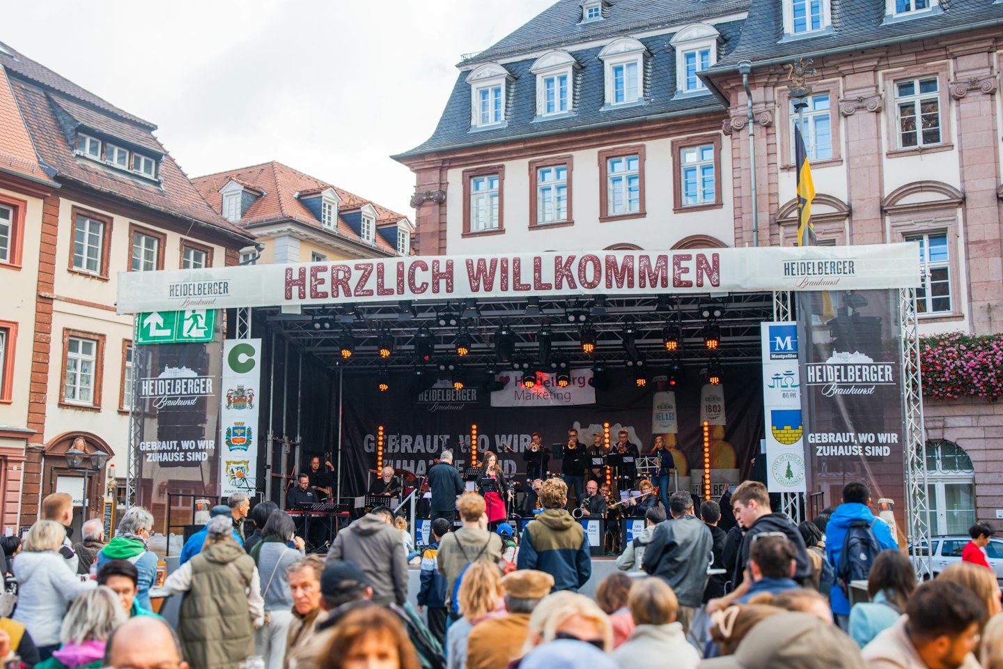 A live band performs on a stage before a large crowd.